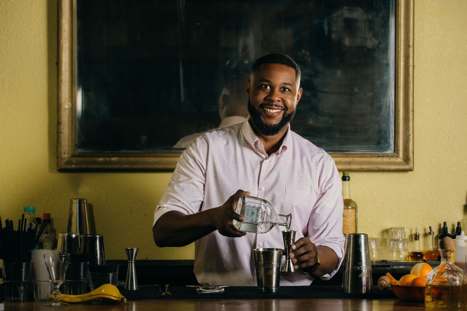Bartender preparing cocktail behind bar counter.