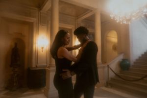 A romantic couple embraces in a dreamy atmosphere within a grand historic building with vintage lighting.