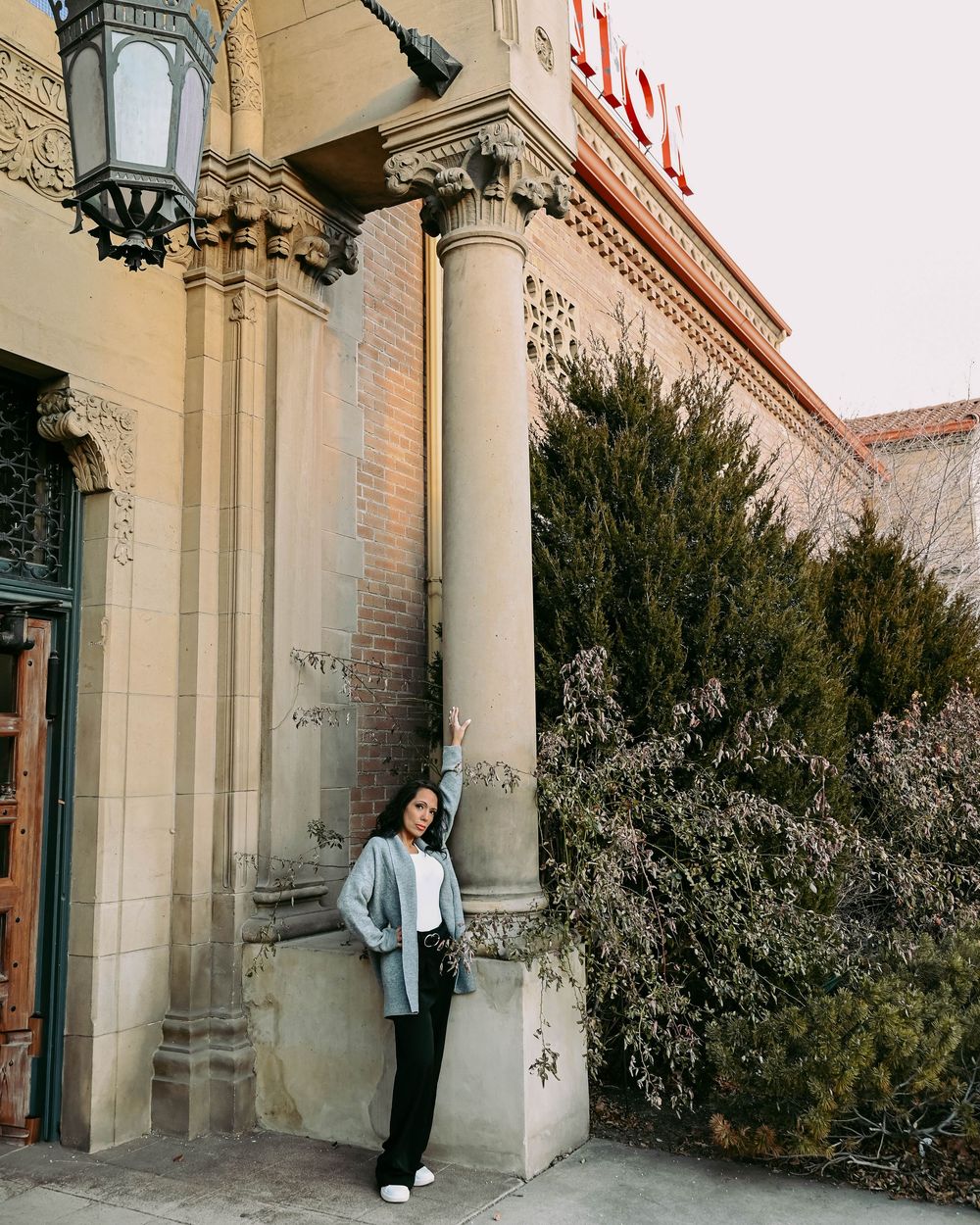 A fashion portrait showcasing a casual outfit against classic stone columns and architectural details.