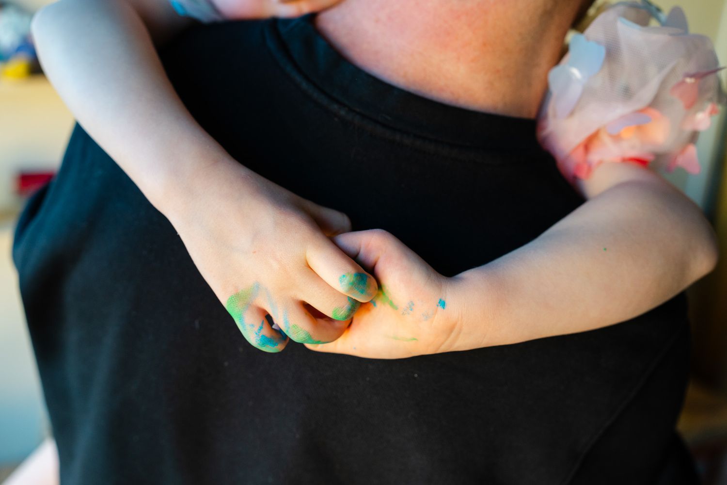Familjen sitter i sängen och busar under familjefotograferingen i hemmet.