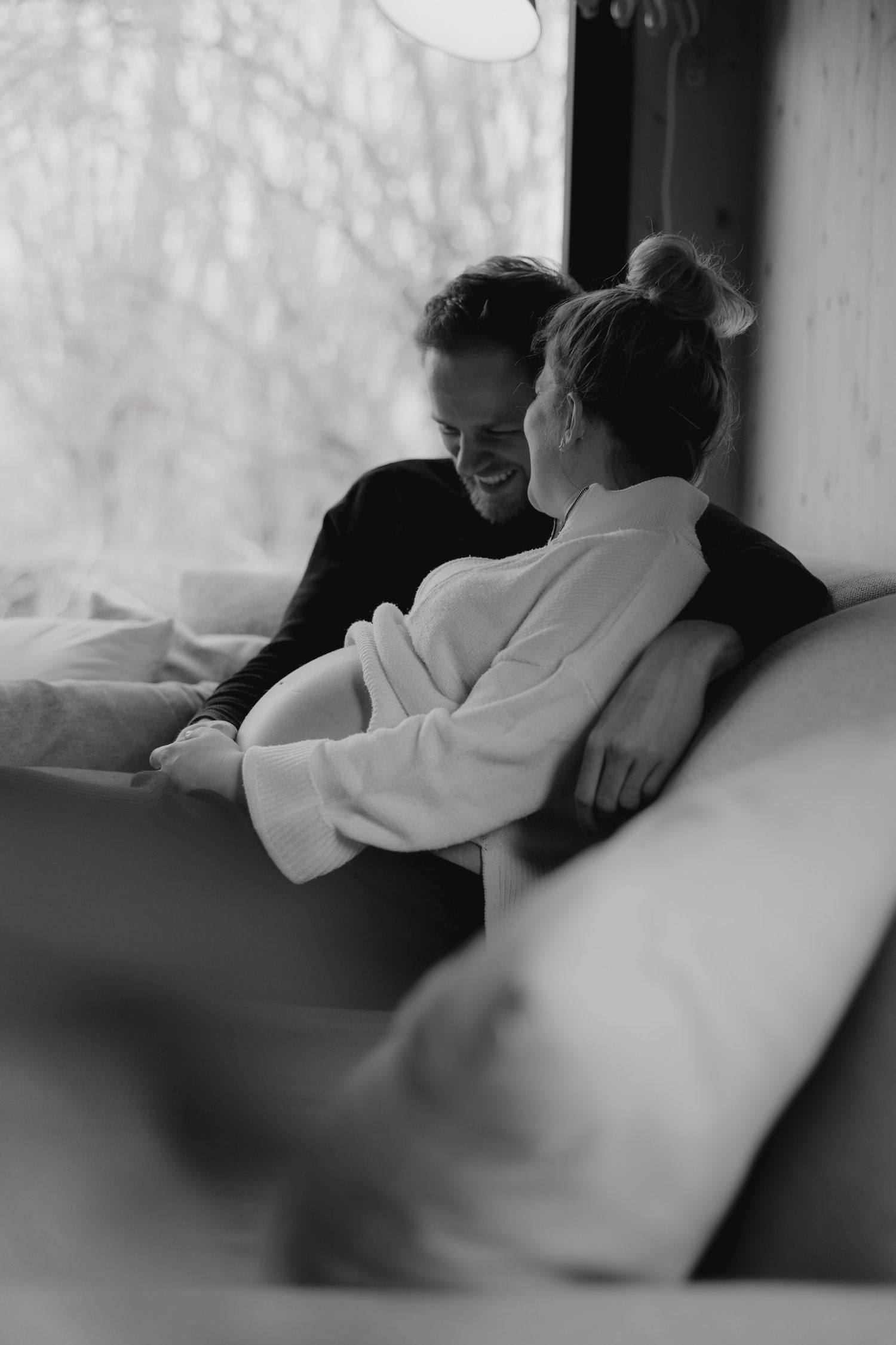 Intimate black and white photo of couple sharing tender moment on couch.