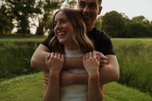 Happy couple sharing playful moment in sunlit field during summer evening.
