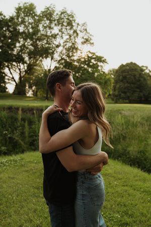 Romantic embrace captured in golden evening light on green summer meadow.
