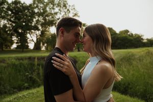 Intimate portrait of couple against sunset backdrop in natural setting.