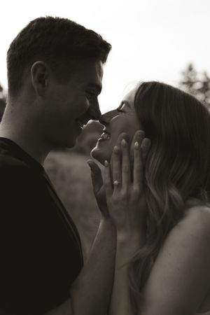A close-up romantic moment between a couple in black and white.