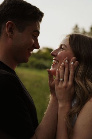 A joyful engagement moment captured in natural lighting with visible ring.