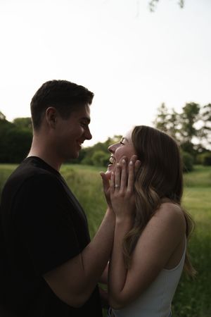 Two people share an emotional moment against a bright natural background.
