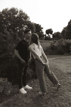 A playful black and white portrait of a couple in a garden setting.