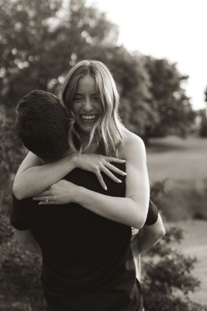 A joyful embrace captured in black and white photography outdoors with natural lighting.