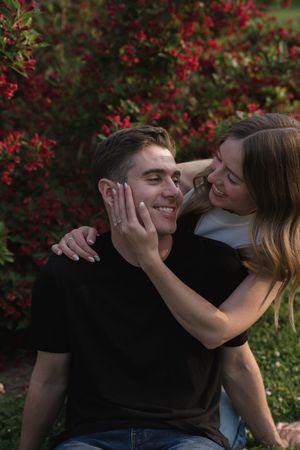 A couple shares an intimate moment against a backdrop of vibrant red flowers.
