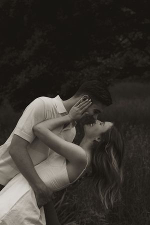 A romantic dip pose photographed in dramatic black and white outdoors.