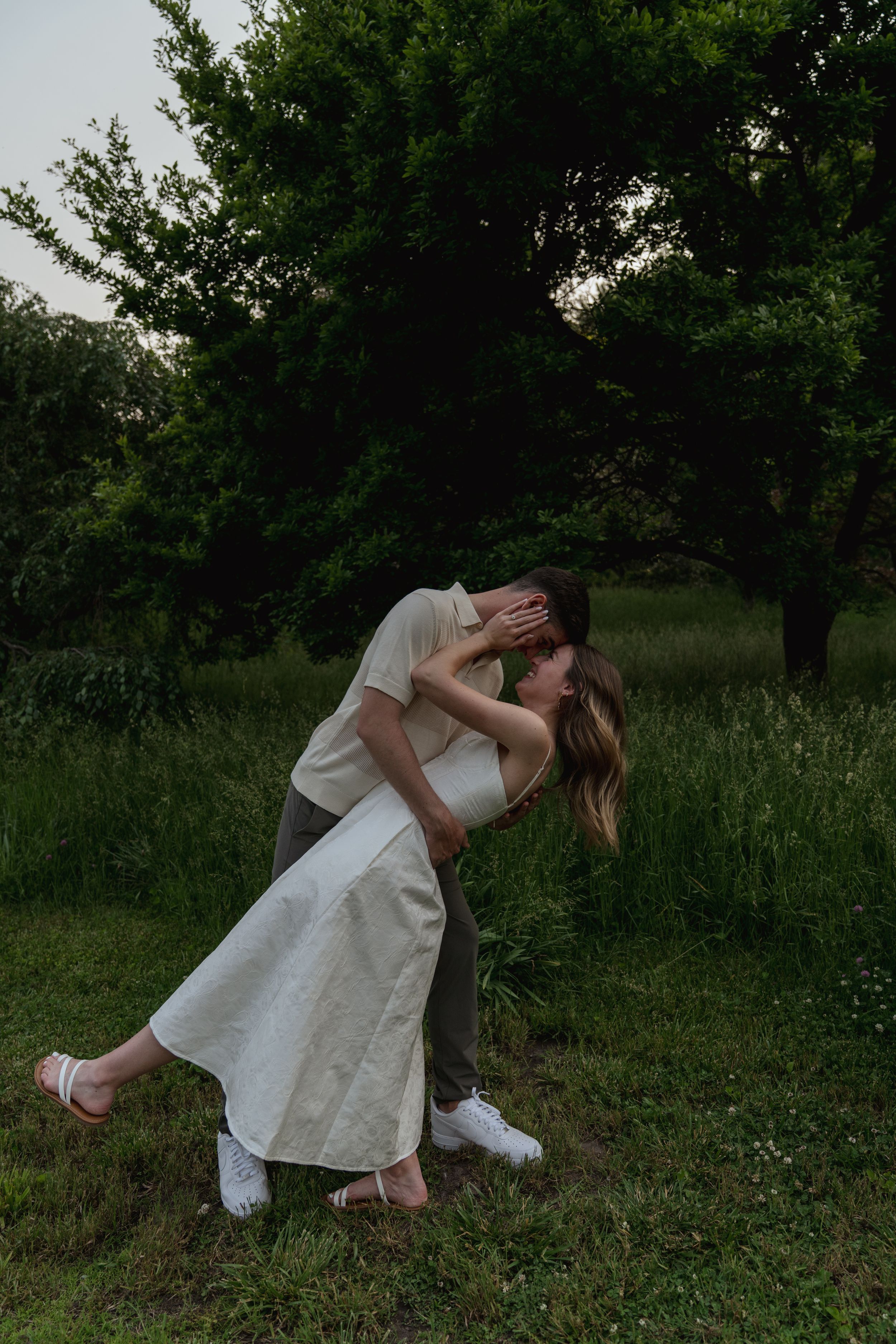 A romantic dance pose in a green meadow at dusk.