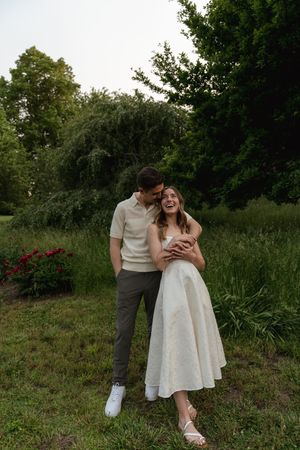 A playful couple shares an intimate moment while standing in a garden.