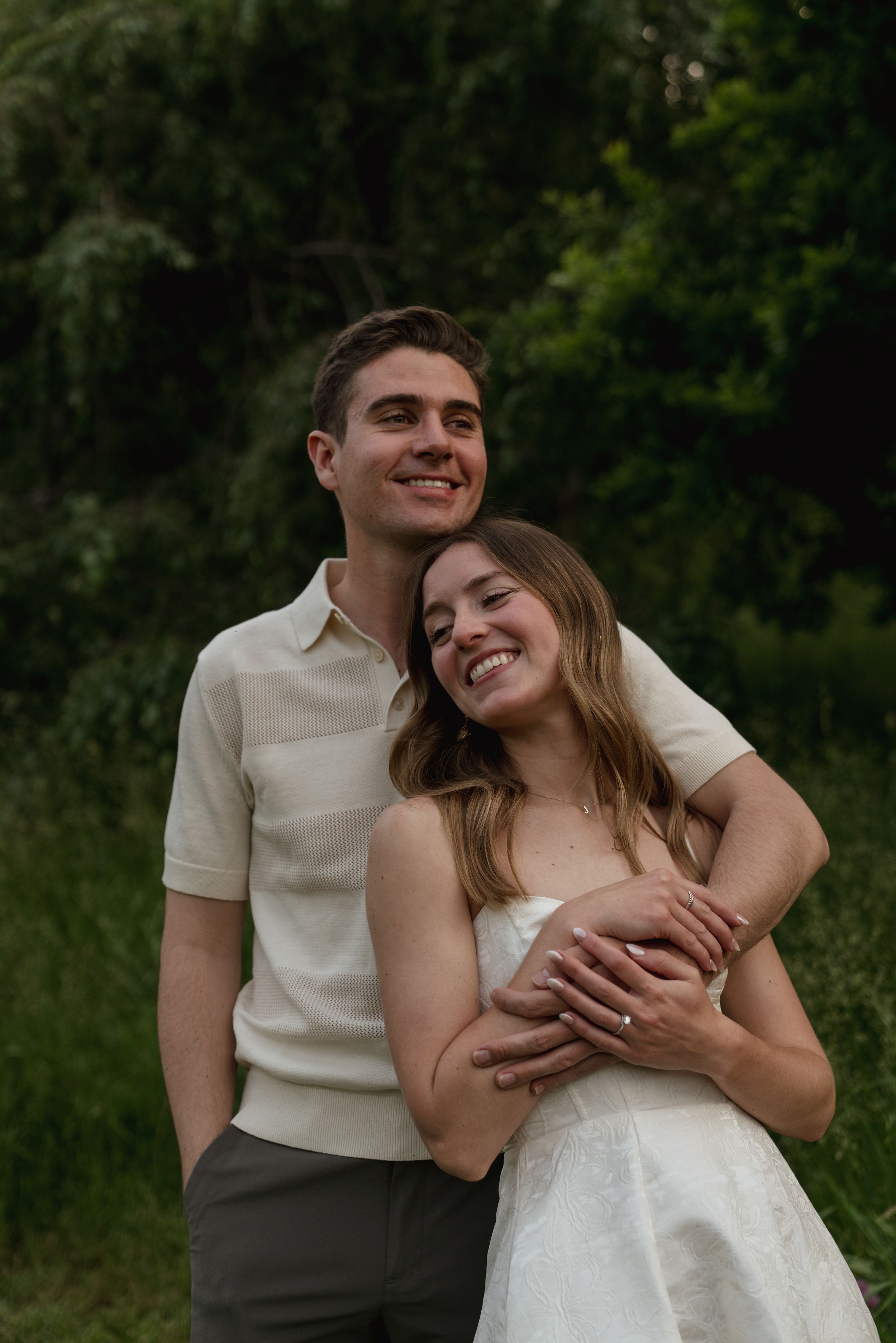 A joyful couple embraces and laughs together in a natural outdoor setting.