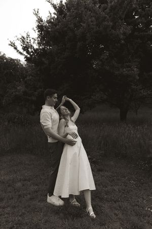 A couple dancing together outdoors in vintage-style black and white photography.