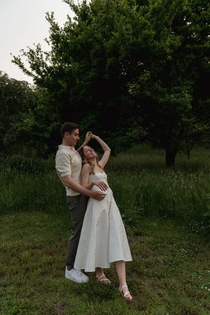 A couple shares a romantic dance move in an outdoor garden setting.
