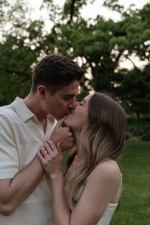 Intimate couple sharing tender kisses in a natural outdoor setting with greenery in the background.