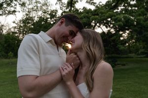 A romantic moment captured between two people in a serene outdoor setting at sunset.