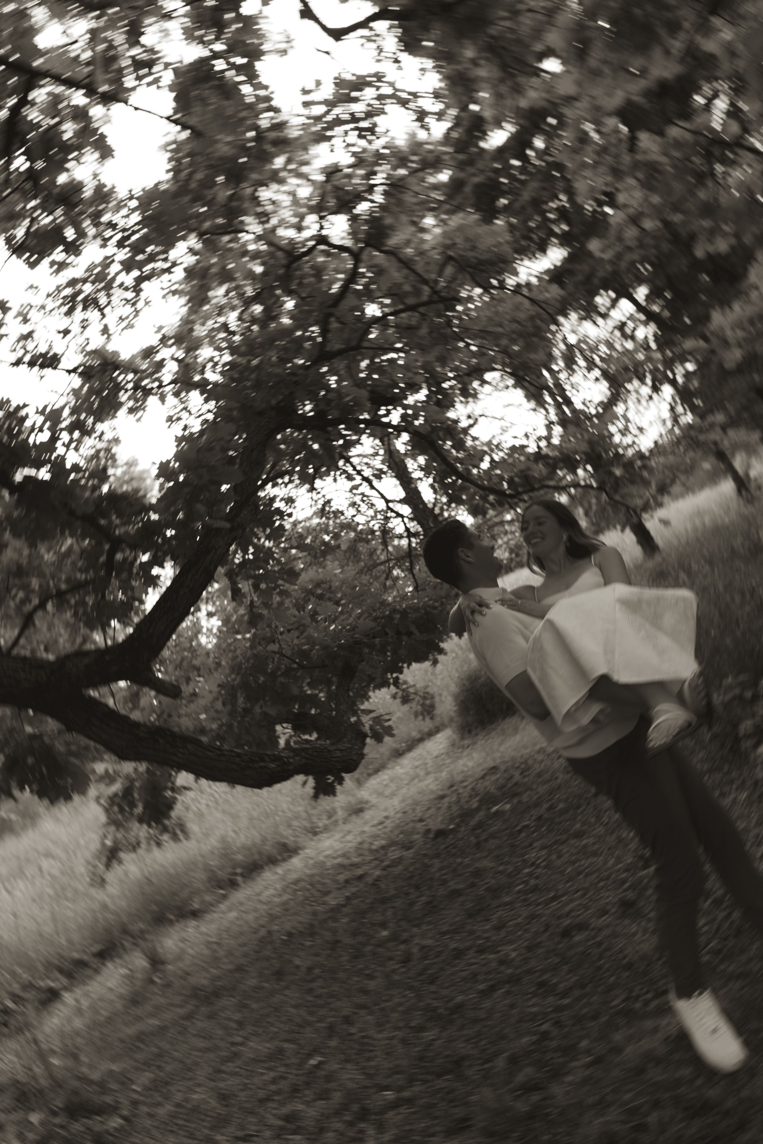 A black and white photo captures a playful moment under a large tree branch.