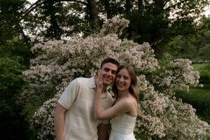 A romantic engagement photo with cherry blossoms blooming in the background.