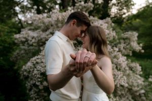 A couple sharing an intimate moment surrounded by blooming cherry blossom trees.