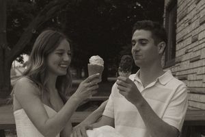 A sweet moment captured as a couple enjoys ice cream together by a stone wall.
