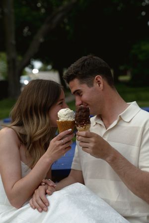 Two people share a tender moment while enjoying ice cream together outdoors.