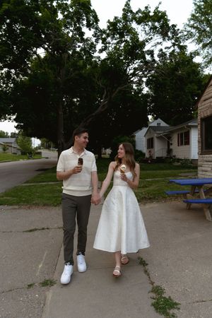 A couple enjoying ice cream cones while walking together on a summer evening.