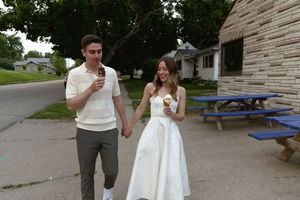 A romantic moment shared between two people walking outdoors near picnic tables.