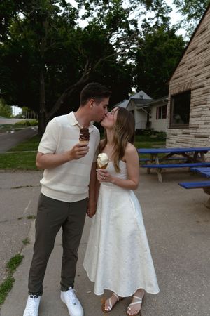 A couple sharing ice cream and laughter together outside on a warm day.