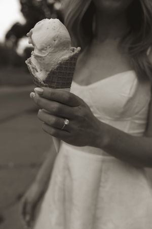 Close-up black and white shot of ice cream cones being held in hands.