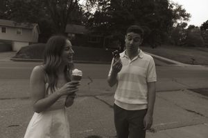 Two people enjoying ice cream cones while walking together outdoors.