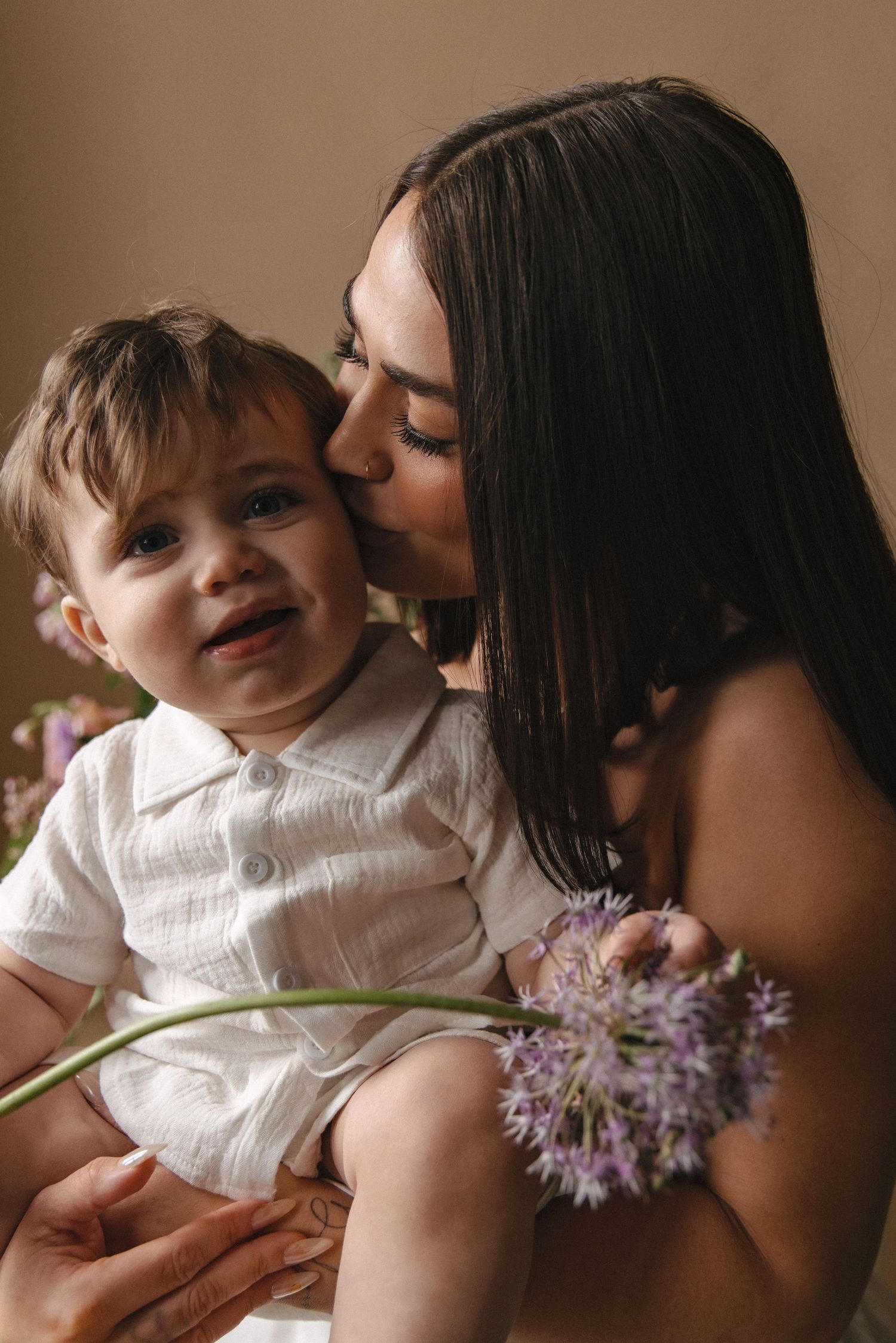 A tender moment captured in a series of photos showing a parent and toddler with purple spring flowers in warm lighting.