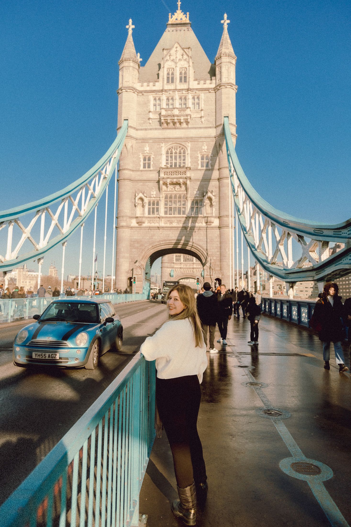 Tourist photo on Tower Bridge walkway with classic London architecture and blue sky backdrop.