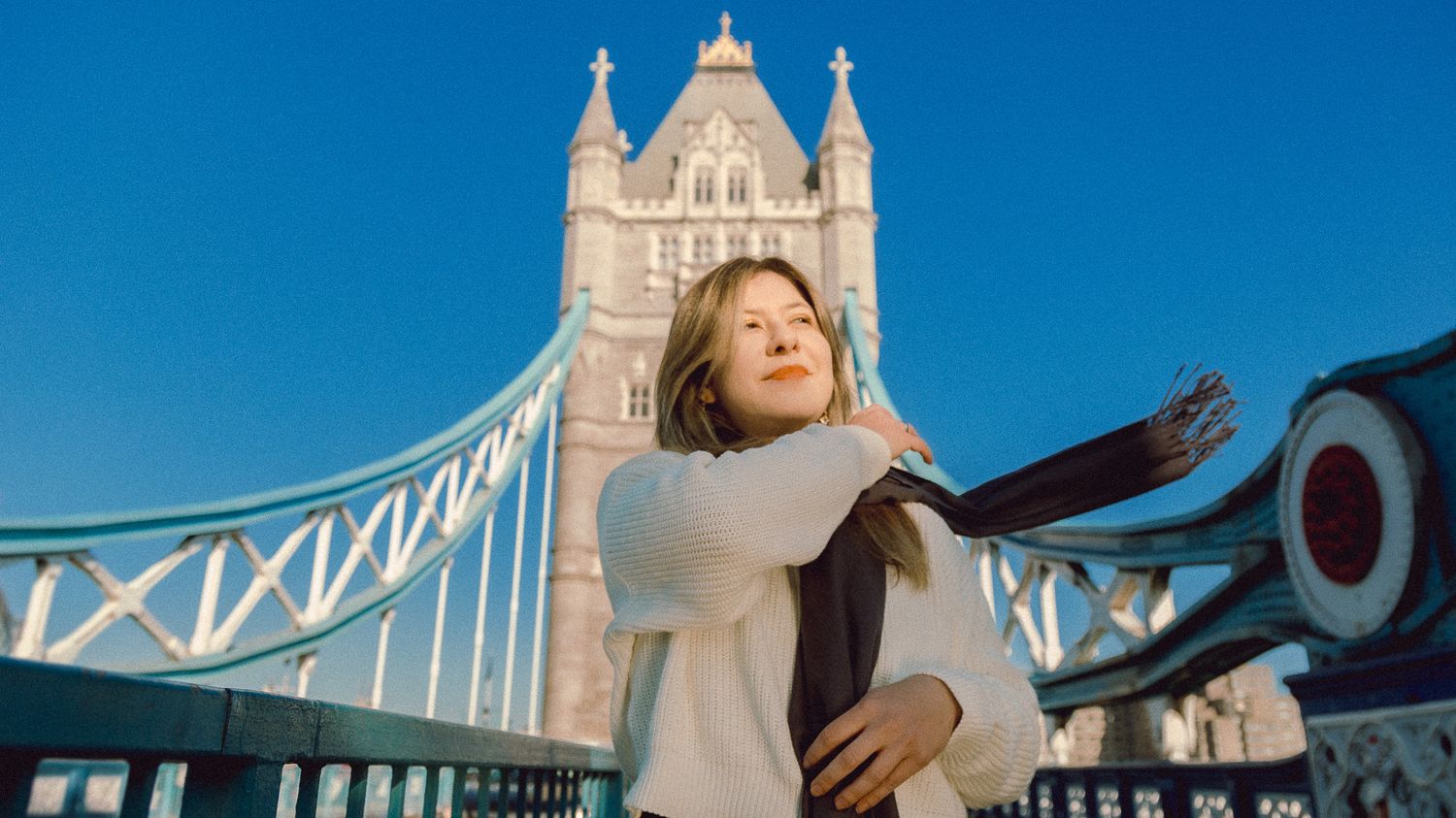 Candid shot against Tower Bridge's Gothic architecture on sunny winter day.