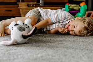 A sequence of someone lying on the floor alongside a white toy bunny in a bright indoor setting.
