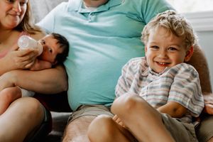 A joyful family moment on a couch shows intimate bonding time at home in natural light.