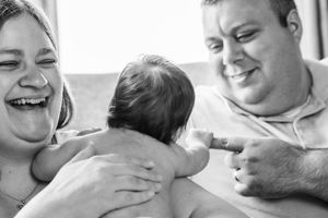 Black and white candid photo capturing joyful family moment with new baby.