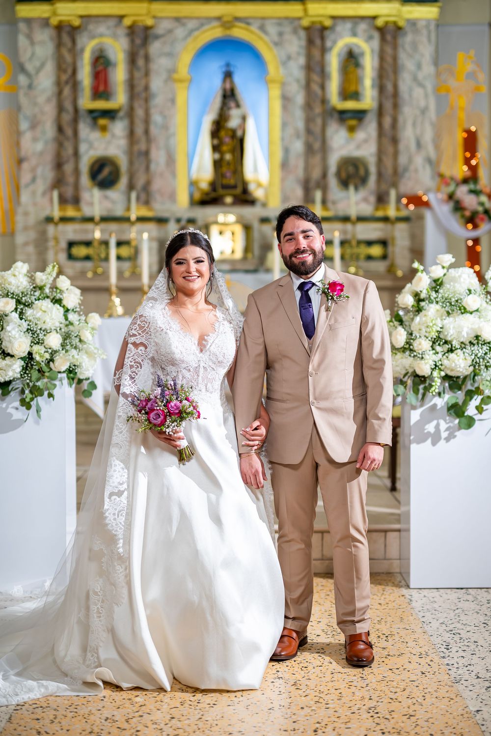 A traditional wedding scene in an ornate church decorated with white floral arrangements and golden accents.