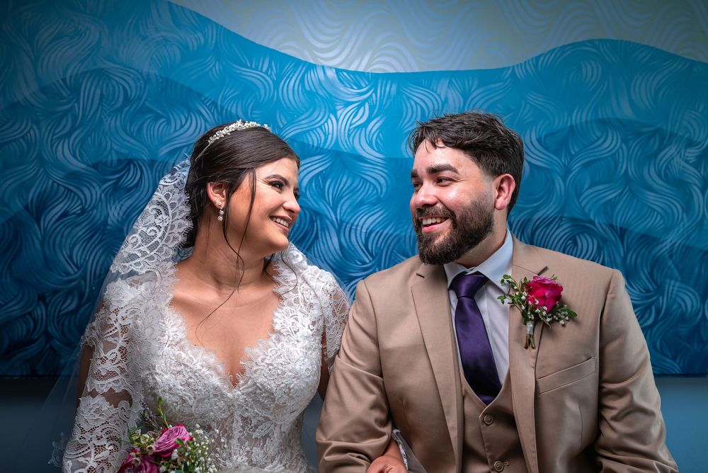 Wedding portraits captured against a vibrant blue patterned wallpaper background showing joyful candid moments.