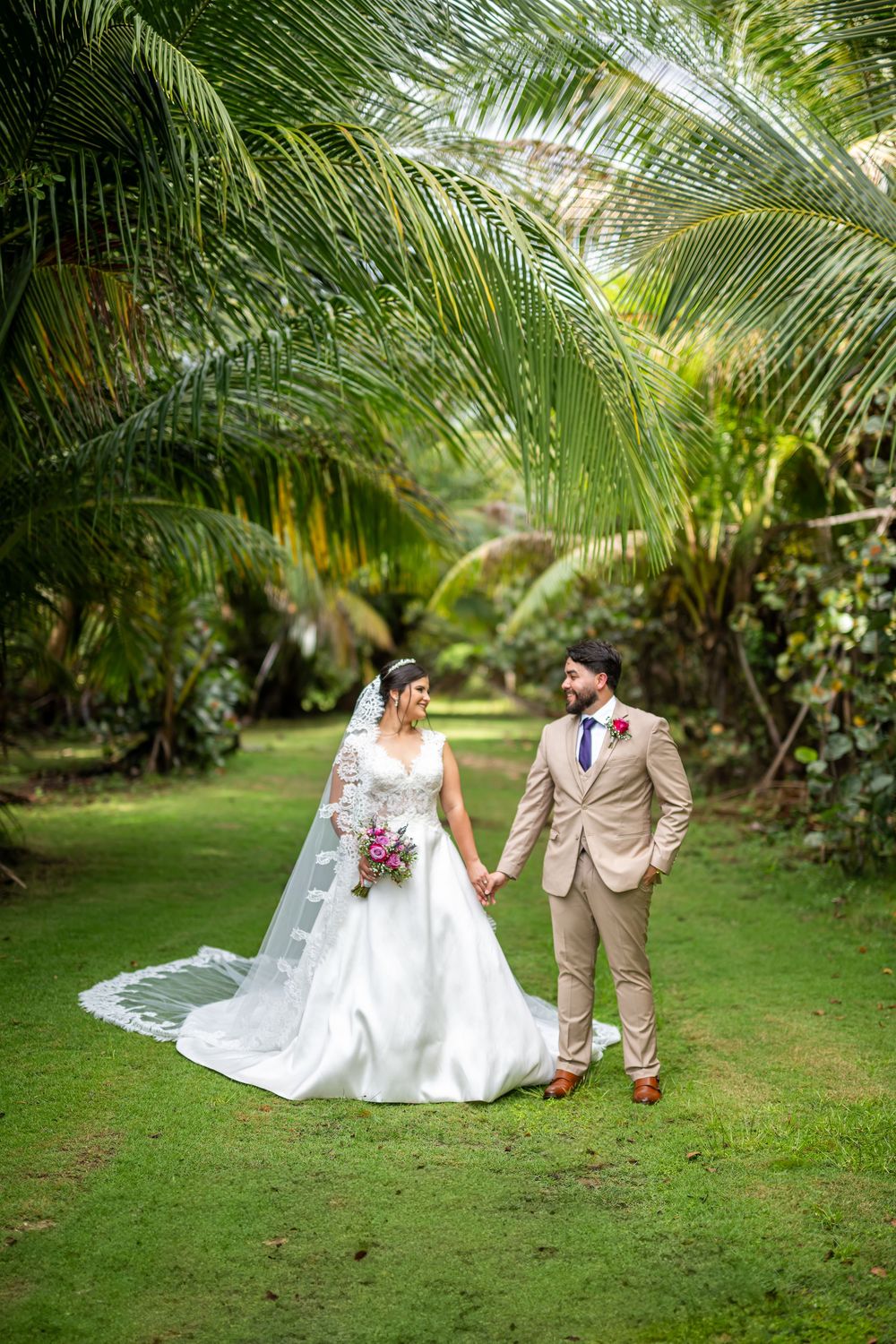 A romantic tropical garden wedding portrait with palm trees and lush greenery surrounding the couple.