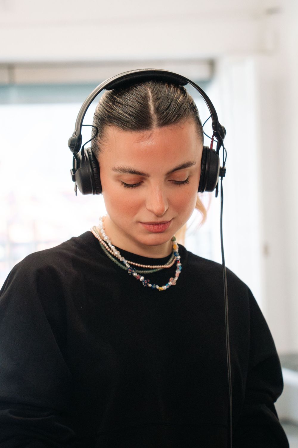 Person wearing headphones and black clothing in close-up portrait sequence against white background.