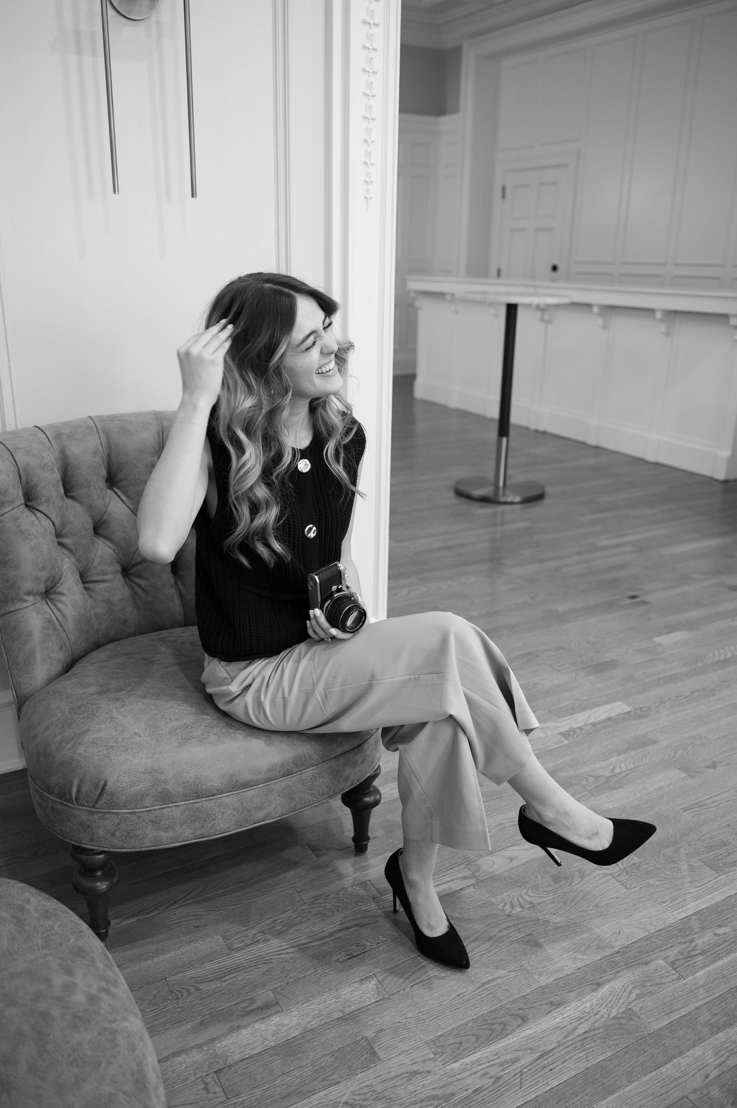 Black and white photo of a tufted chaise lounge in an elegant room.