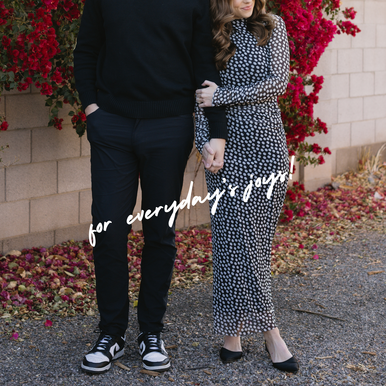Couple posing in contrasting outfits against pink bougainvillea wall, showing casual and formal style together.