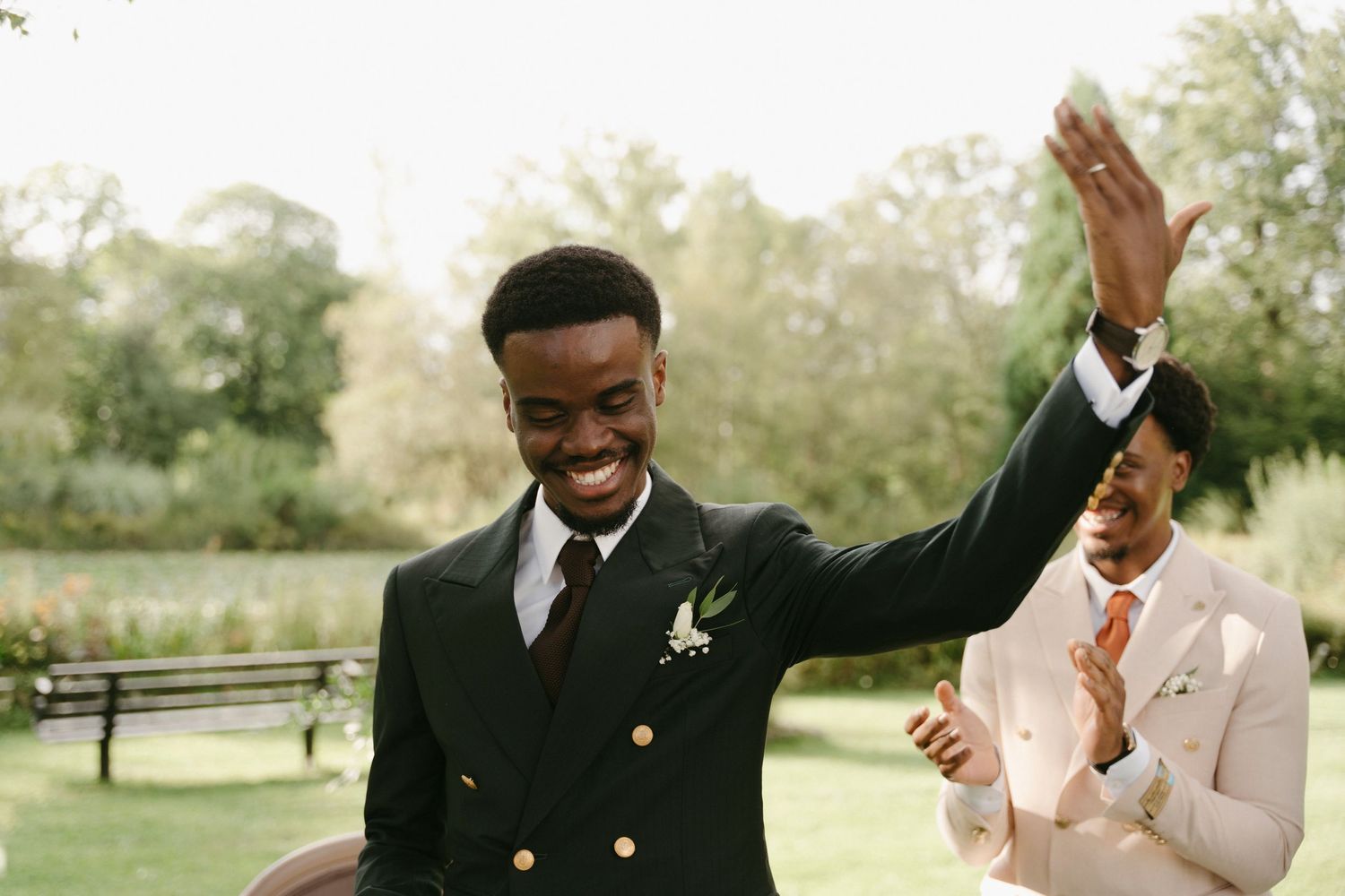 A joyful celebration moment at an outdoor wedding with raised hands and formal attire.