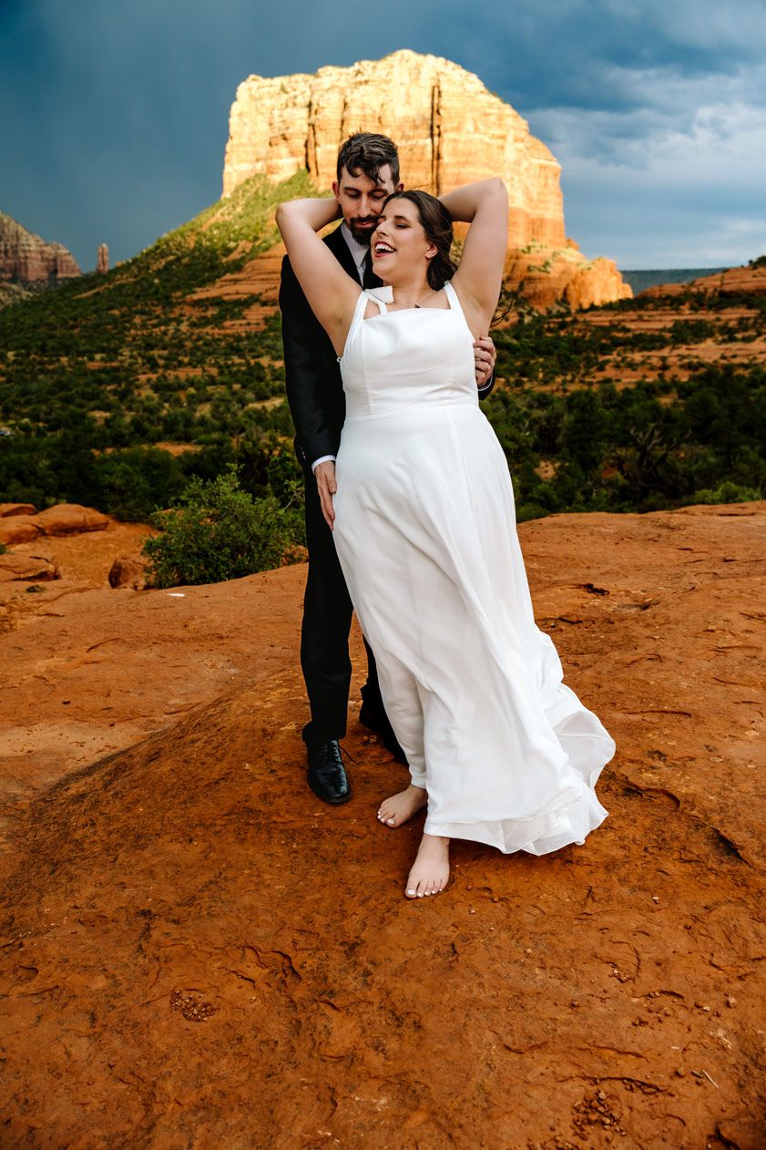 A dreamy wedding portrait with flowing white dress against towering desert cliffs.