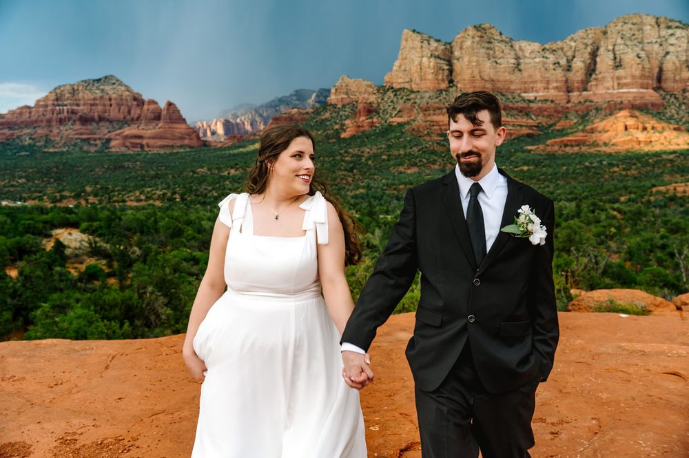 A candid wedding moment captured on red rocks with Sedona's dramatic landscape behind.