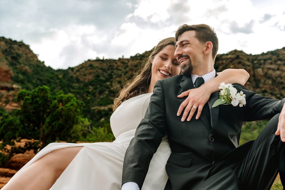 Joyful wedding couple sharing a candid moment against Sedona desert mountain backdrop.
