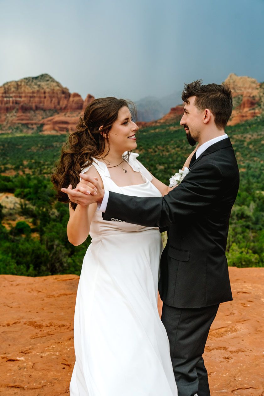Wedding couple dancing together on Sedona red rock formations in Sedona.
