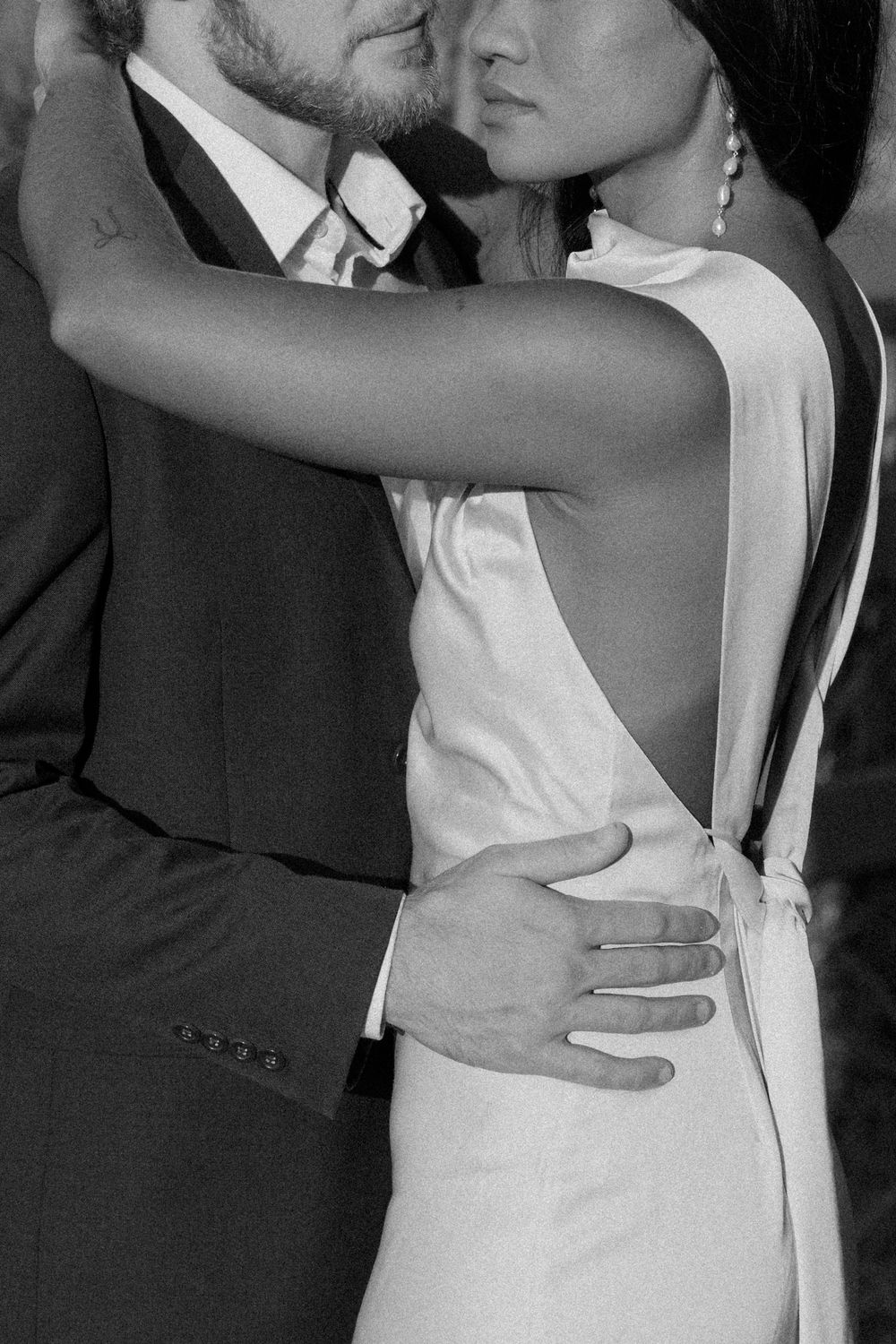 An intimate black and white portrait showing details of a couple in formal attire.